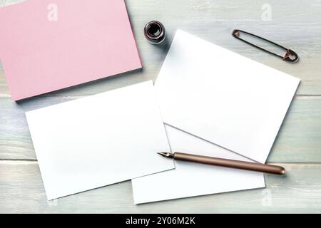 Stationery mock-up with an ink bottle, a nib pen, and a vintage pin. Blank retro fashion greeting cards or invitations, shot from above with a place f Stock Photo