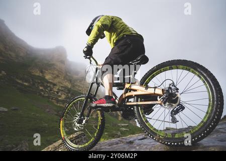 Extreme mountain bike sports athlete man in helmet riding outdoors against a background of rocks. Lifestyle. Trial Stock Photo