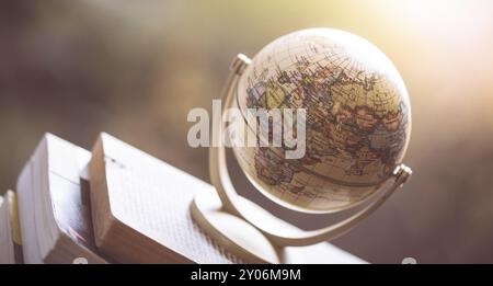 Miniature globe model standing on a stack of books. Symbol for travelling Stock Photo
