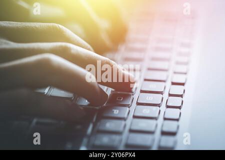 Close up picture of hands typing on a notebook keyboard, sunshine Stock Photo