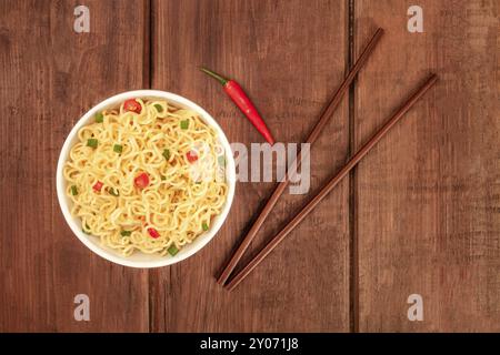 An overhead photo of a bowl of noodles with chopsticks and copy space, on a dark rustic background texture Stock Photo