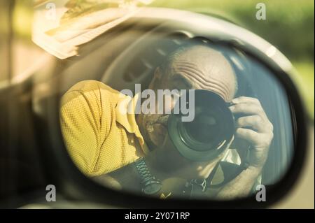 Reflection of a photographer in the rear-view mirror of a car Stock Photo