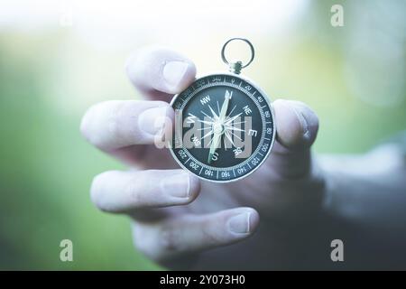 Young man on an adventure is holding a compass in his hand for finding is route Stock Photo