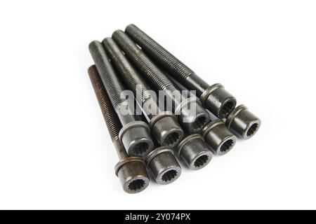 A set of new cylinder head bolts in oil on a white isolated background are shot in perspective at a wide angle. Spare parts for car repair Stock Photo