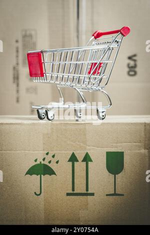 Online-Shopping and parcel service concept: Miniature shopping cart and cardboard boxes Stock Photo