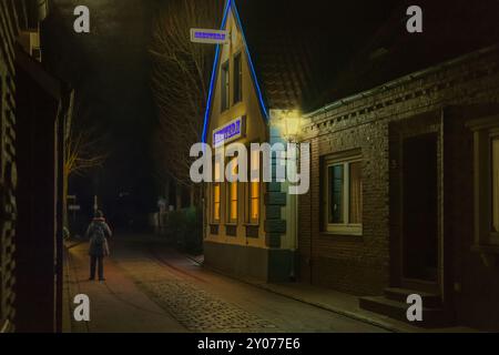 Lonely woman in the alleyway of an East Frisian fishing village at night Stock Photo