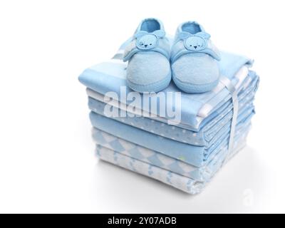 Cute blue baby boy shoes on a pile of swaddling blankets isolated on white background Stock Photo