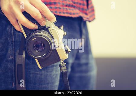 Man is holding a vintage camera in his hand, jeans and shirt Stock Photo