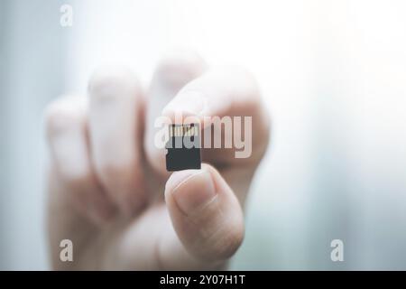 Young man is holding a tiny memory card in his hand, text space Stock Photo