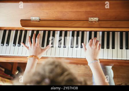 Young girl is practicing piano at home. Clipping of piano and hands Stock Photo