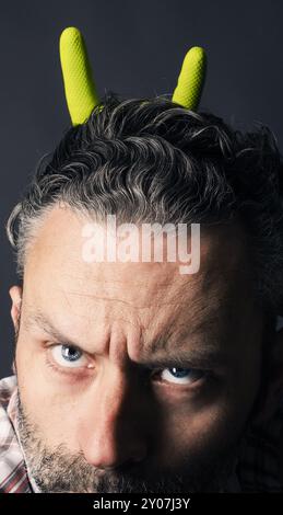 Angry man with grin on his handsome bearded face hand with rock metal gesture on a dark background Stock Photo