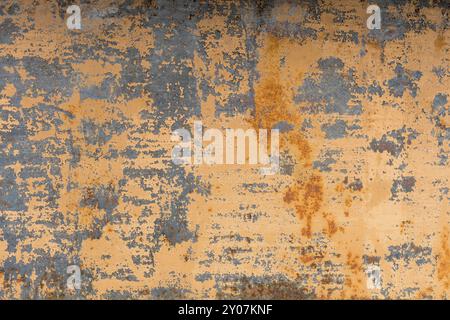 Textured background of a faded yellow paint with rusted cracks on rusted metal. Grunge texture of an old painted and cracked metal surface. Rusty yell Stock Photo