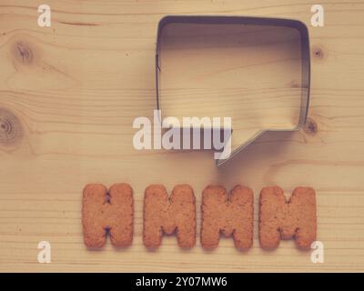 The word Hmmm with a speech bubble on a wooden table Stock Photo