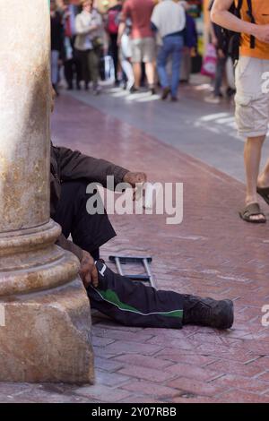 Beggar sitting on the street of a pedestrian zone Stock Photo