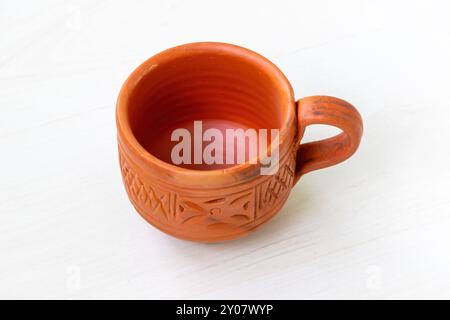 Beautiful cup made of clay placed on light wooden surface. Stock Photo