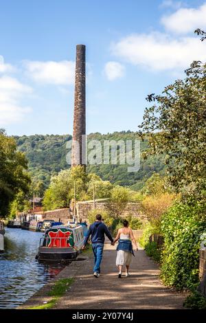 Couple walking had in hand along the Rochdale canal in the Calderdale Valley market town of Hebden Bridge West Yorkshire England Stock Photo