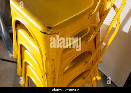 A closeup view of stacked yellow retro metal chairs. Stock Photo