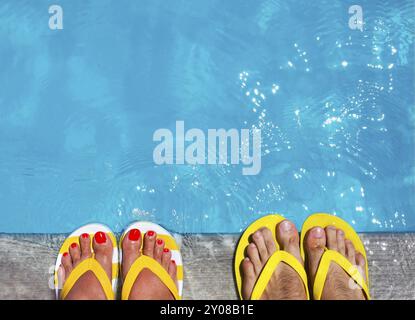 Feet in flip flops on stone background on poolside. Summer family vacation concept Stock Photo