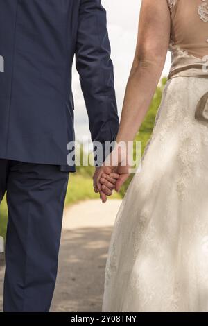 Walking wedding couple from behind holding hands Stock Photo