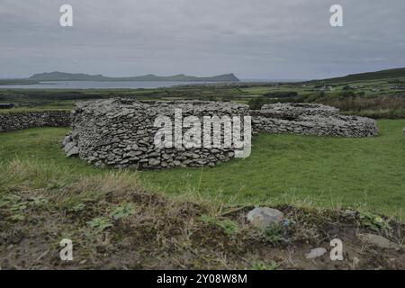 A roadside view of a ring fort on the Dingle peninsula with the mountain peaks known as the Three Sisters in the background. County Kerry, Ireland, Eu Stock Photo