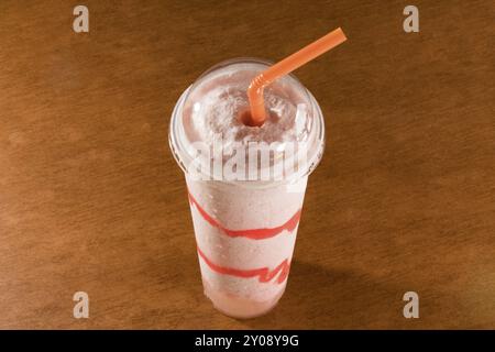 Fresh strawberry smoothie in plastic cup on ceramic floor tile Stock Photo