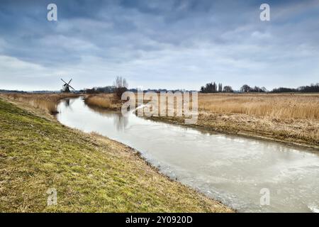 Frozen river and dutch windmill in clouded morning Stock Photo