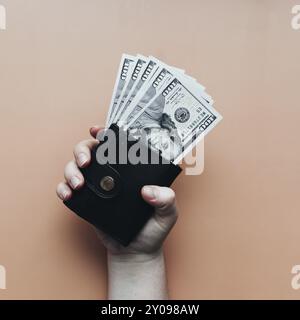 Bundle of dollars in purse and hand on beige background. Stock Photo