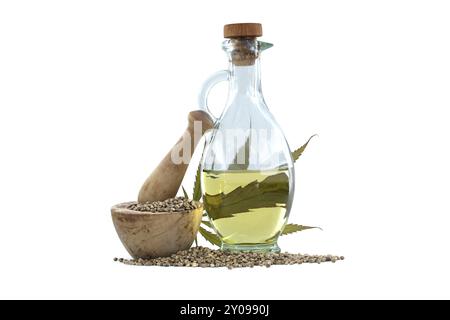 Hemp leaf in front of cannabis oil in glass decanter and hemp seeds in wooden mortar on white background Stock Photo