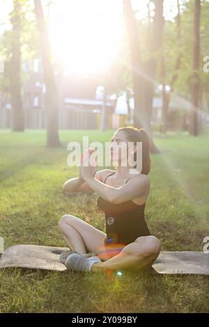 Young woman meditating outdoors in summer sunset park Stock Photo