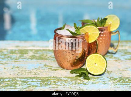Natural lime and lemon homemade lemonade in cooper mugs on rustic wooden background Stock Photo
