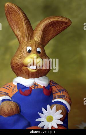 Funny sitting figure of a rabbit with blue dungarees Stock Photo