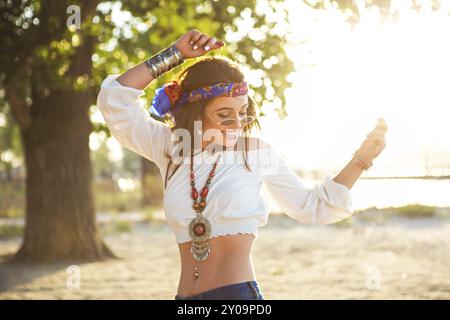 Happy slim tan woman in jeans dancing on the beach in sunset Stock Photo