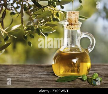 Olive oil and olive branch on the wooden table over nature background Stock Photo