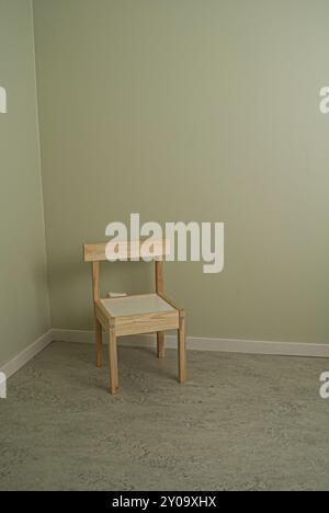 A lonely children's chair in a corner of a light green room Stock Photo