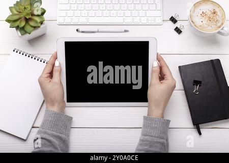 Female hands over desktop, blogger or business woman holding a tablet. Flat lay, overhead view Stock Photo