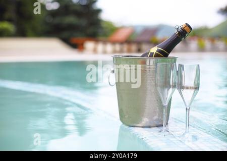 Ice bucket champagne bottle and two glasses near smimming pool Stock Photo