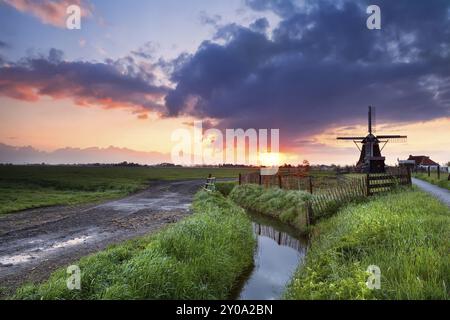 Dramatic warm sunrise over Dutch windmill and river, Groningen, Netherlands Stock Photo