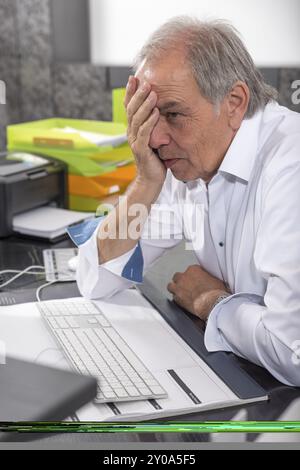 senior man sitting desperately at a desk Stock Photo - Alamy
