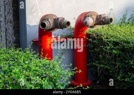 Red fire hydrant near a residential building. A device connected to the water supply for water supply. Stock Photo