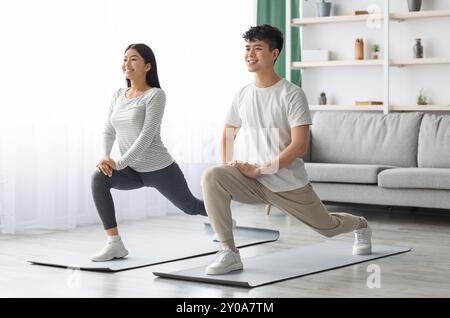Motivated asian couple exercising at home, copy space Stock Photo