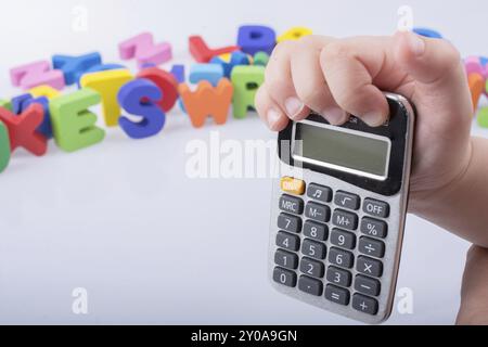 Little calculator in hand with colorful letters behind on white Stock Photo