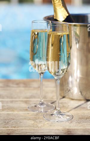 Champagne glasses and bottle in ice bucket near swimming pool. Vacation and romance concept Stock Photo