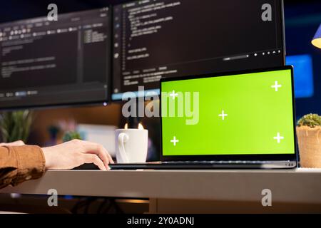 Developer working on isolated screen laptop, futureproofing company network from downtimes and unexpected system failures. Admin using chroma key notebook, increasing data security, close up Stock Photo