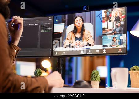 Software engineer teacher doing online tutoring, talking with students in online videocall about ways to do debugging. IT master teaching apprentices in webinar how to write code Stock Photo