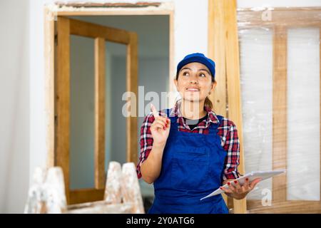 Cheerful woman engineer checking documents in new apartment Stock Photo