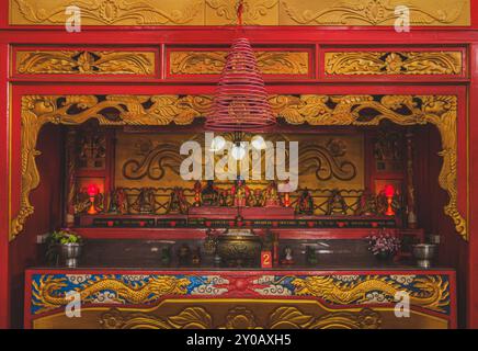 Balikpapan, Indonesia - June 22nd, 2024. a golden altar adorned with intricate carvings and statues of Chinese deities, illuminated by warm light and Stock Photo