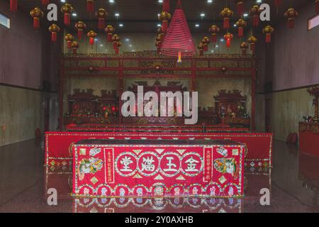 Balikpapan, Indonesia - June 22nd, 2024. The temple features a colorful altar adorned with golden embellishments and statues of Chinese deities. Red l Stock Photo