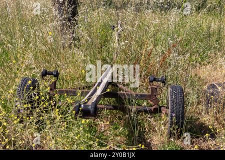 Old rusty and forgotten boat trailer being slowly reclaimed by nature, standing in a field of tall grass Stock Photo