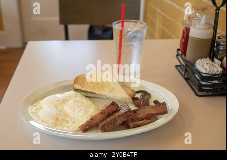 Breakfast of eggs, bacon, toast and hash brown cakes with water Stock Photo