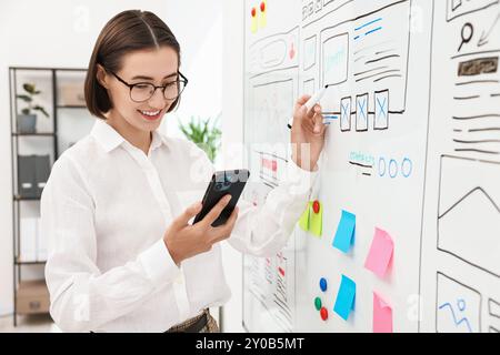 Developing UI design. Woman drawing website wireframe on whiteboard indoors Stock Photo